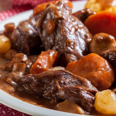 Beef Bourguignon stew served with baked potatoes on a plate. French cuisine